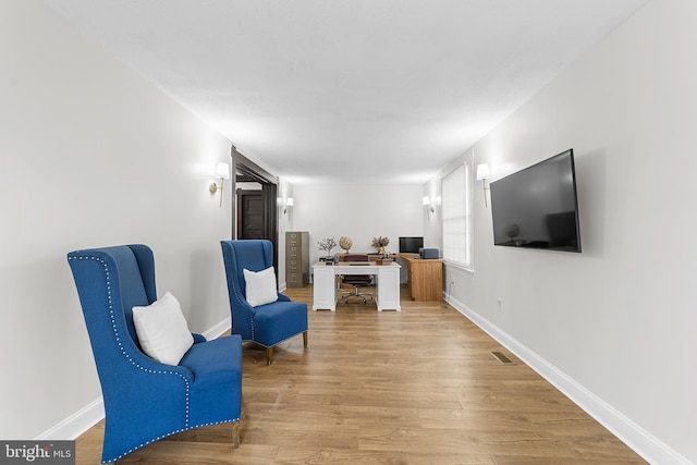 sitting room with visible vents, baseboards, and light wood finished floors