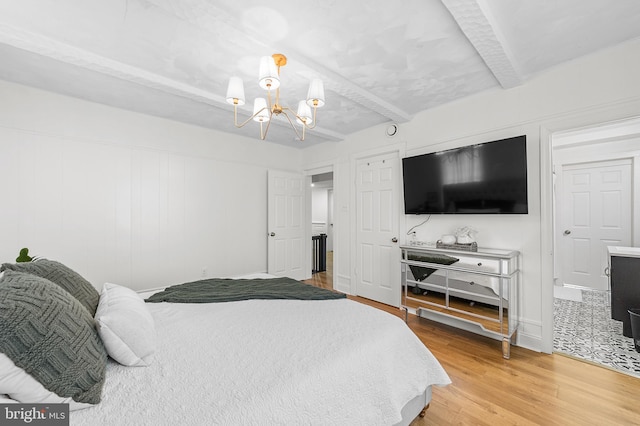 bedroom with a notable chandelier, beamed ceiling, and light wood-style floors