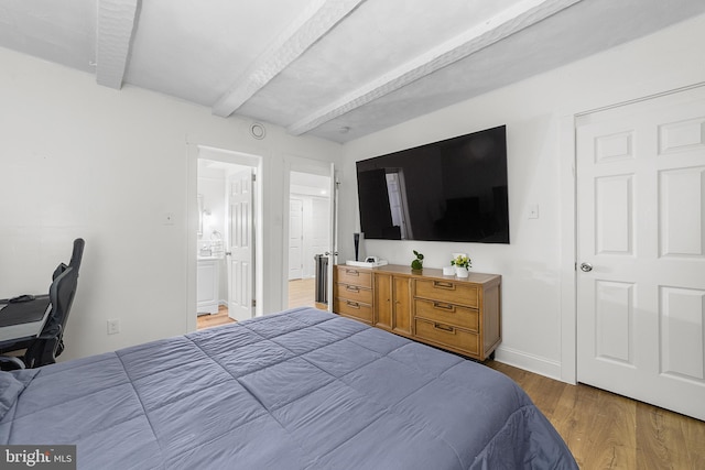 bedroom with beam ceiling, ensuite bathroom, baseboards, and wood finished floors