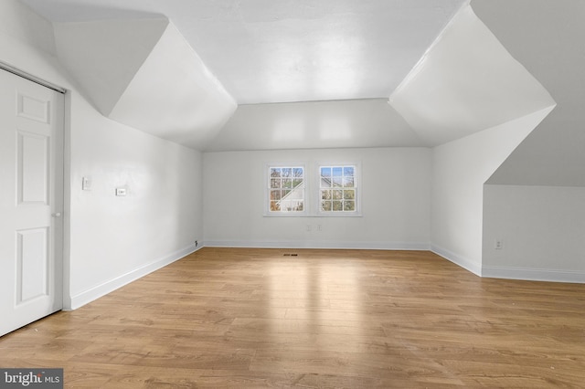 additional living space featuring light wood-style flooring, baseboards, and vaulted ceiling