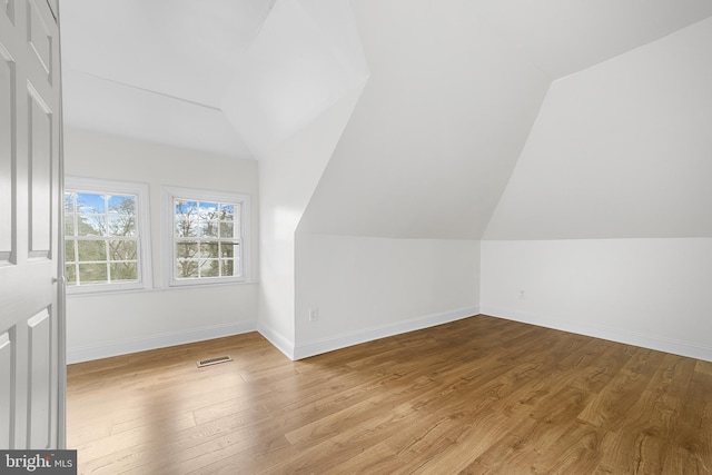 bonus room featuring visible vents, baseboards, wood finished floors, and vaulted ceiling