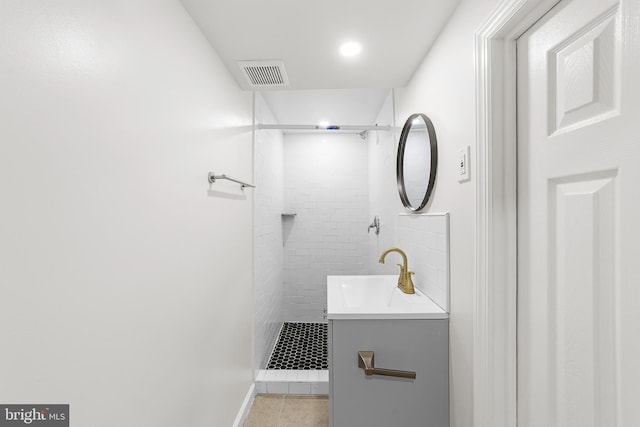 bathroom with tile patterned floors, visible vents, tiled shower, and vanity