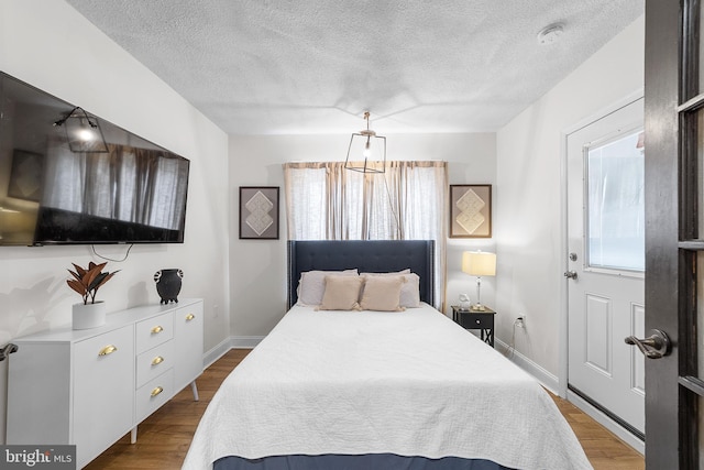 bedroom with a textured ceiling, baseboards, and wood finished floors