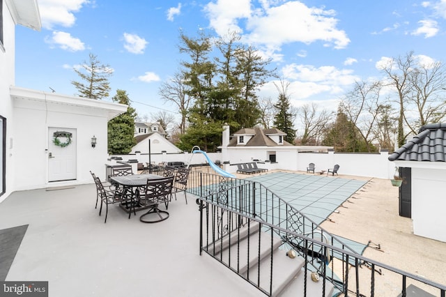 view of patio with outdoor dining area, a fenced in pool, and fence