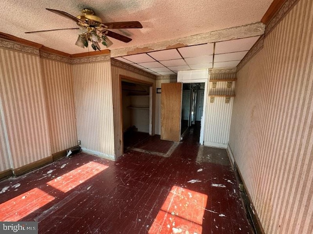 spare room with wallpapered walls, a paneled ceiling, baseboards, and wood finished floors