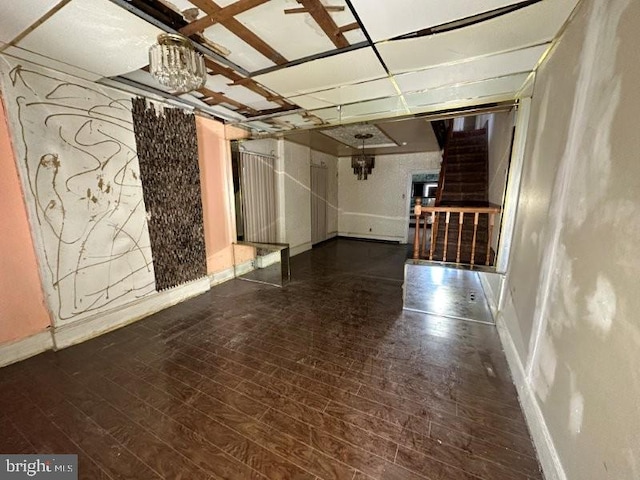 unfurnished room with baseboards, an inviting chandelier, and wood finished floors