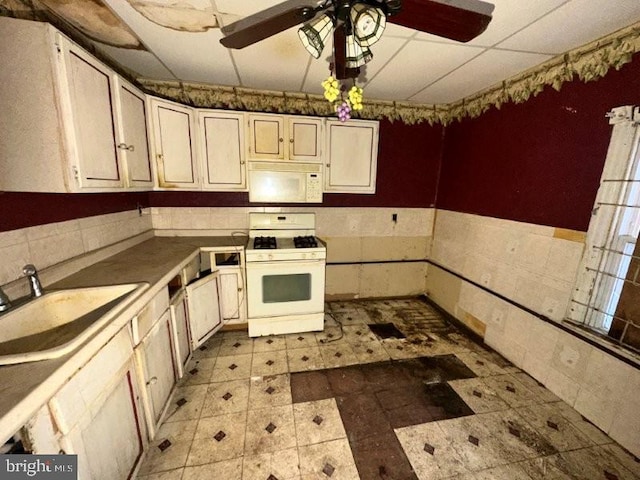 kitchen with light floors, white appliances, ceiling fan, and a sink