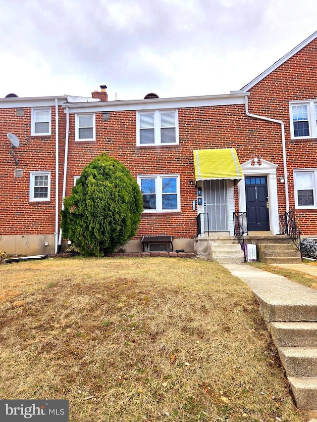 multi unit property with a front yard, brick siding, and a chimney