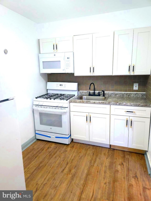 kitchen featuring a sink, backsplash, white appliances, light wood-style floors, and white cabinets