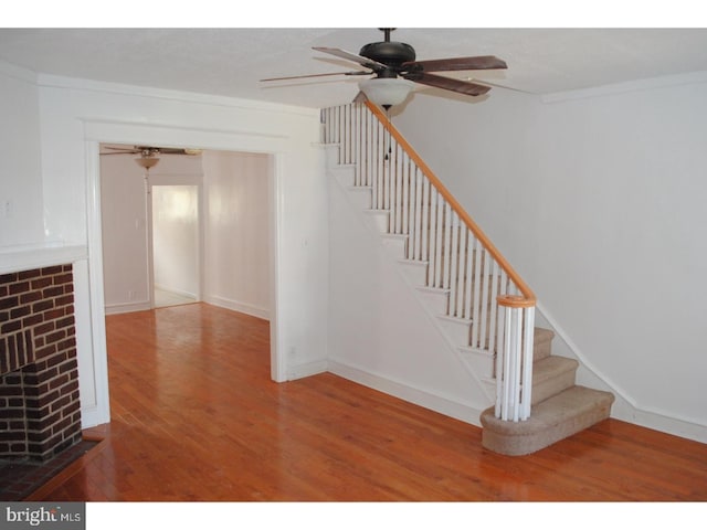 4408 Sherwood Rd, Philadelphia, PA 19131 - stairs featuring ceiling fan, wood finished floors, a fireplace, and crown molding