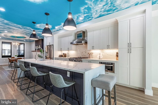 kitchen with white cabinets, appliances with stainless steel finishes, light wood-type flooring, and wall chimney range hood