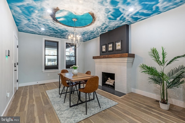 dining area with a notable chandelier, a raised ceiling, baseboards, and wood finished floors