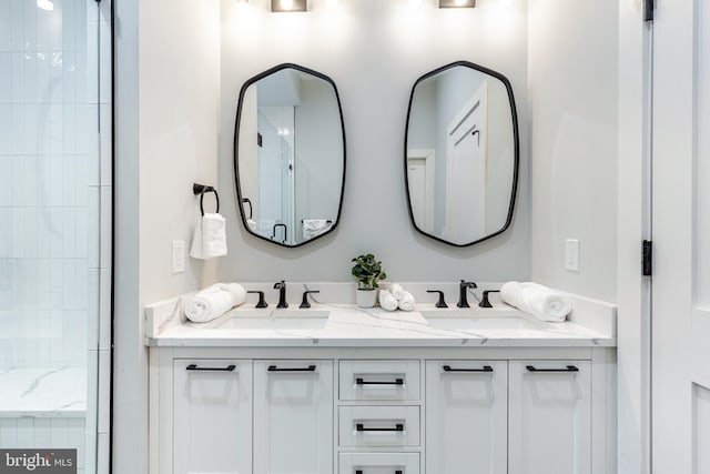 full bathroom featuring a sink, a shower with shower door, and double vanity