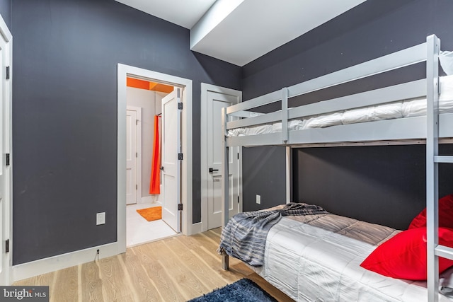 bedroom with ensuite bath and wood finished floors