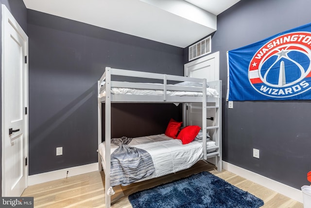 bedroom with wood finished floors, visible vents, and baseboards