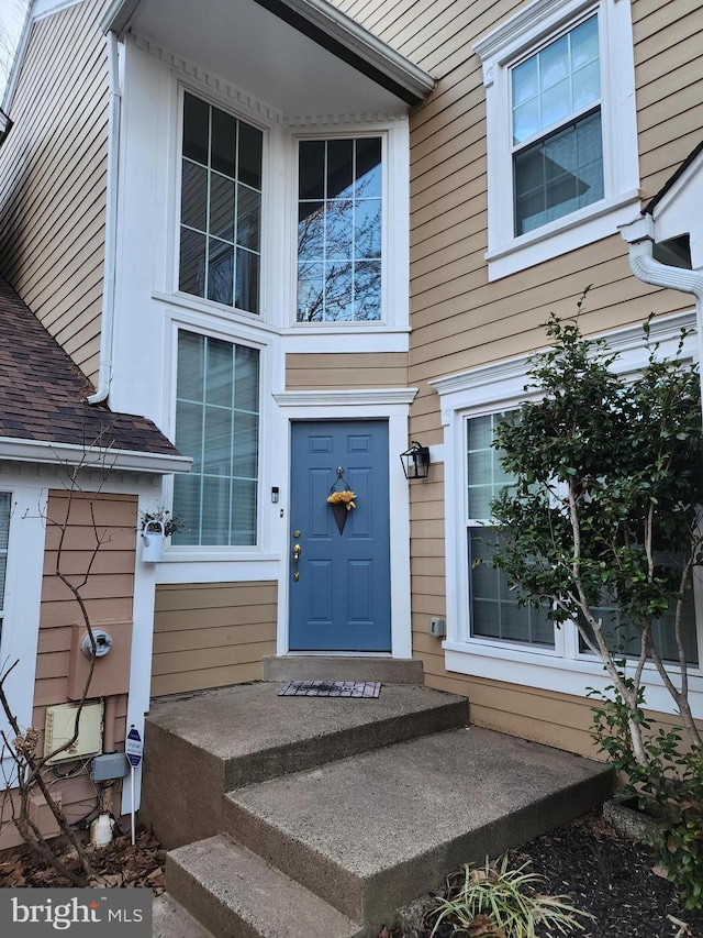 view of exterior entry with roof with shingles