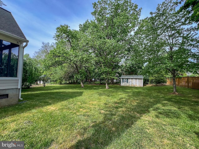 view of yard featuring an outdoor structure, a sunroom, fence, and a shed