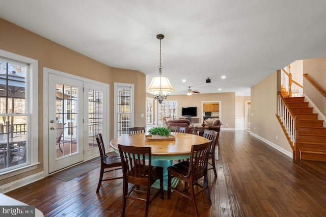 dining area featuring a wealth of natural light, a chandelier, dark wood finished floors, and stairs