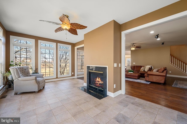 interior space featuring a high end fireplace, baseboards, ceiling fan, stairway, and light tile patterned floors