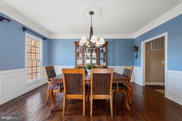 dining room with hardwood / wood-style floors, an inviting chandelier, a wainscoted wall, and visible vents