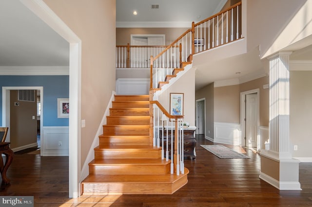 stairs featuring visible vents, hardwood / wood-style floors, wainscoting, and ornamental molding