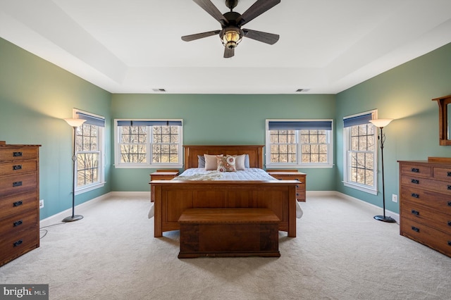 bedroom featuring light carpet, visible vents, multiple windows, and a tray ceiling