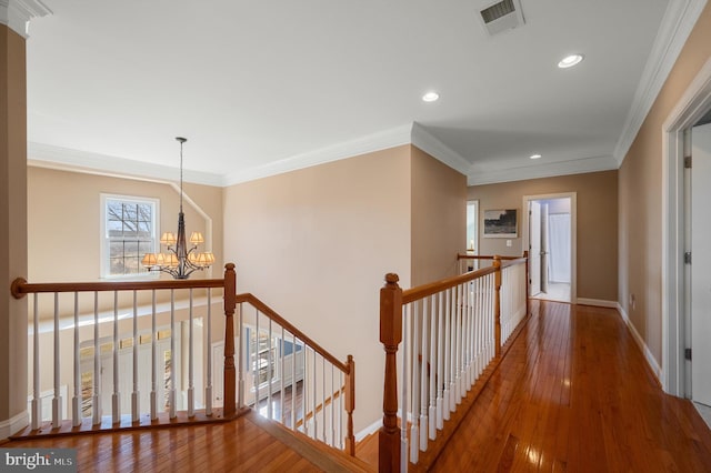 corridor featuring hardwood / wood-style floors, an inviting chandelier, an upstairs landing, and visible vents