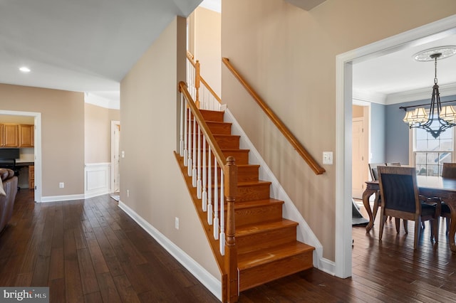 stairway featuring a chandelier, ornamental molding, baseboards, and wood-type flooring