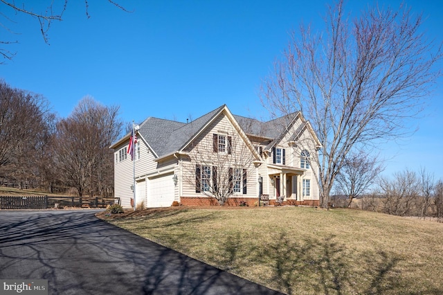 view of front of property featuring a garage, driveway, a front yard, and fence