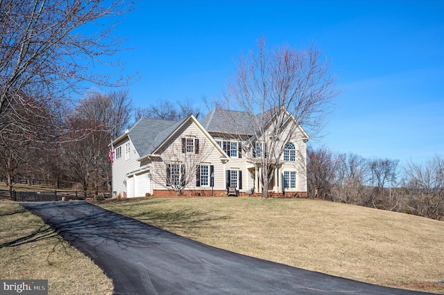 view of front of property featuring aphalt driveway, an attached garage, fence, and a front yard