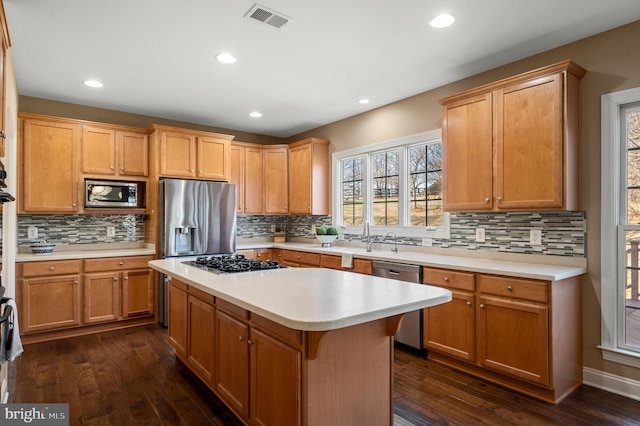 kitchen with stainless steel appliances, visible vents, dark wood-style floors, and light countertops