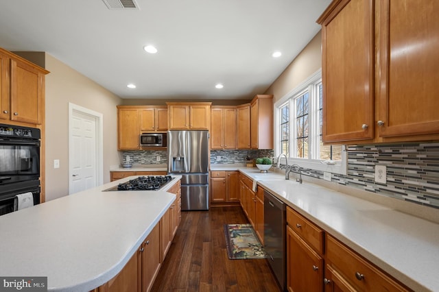 kitchen with tasteful backsplash, dark wood finished floors, light countertops, recessed lighting, and appliances with stainless steel finishes