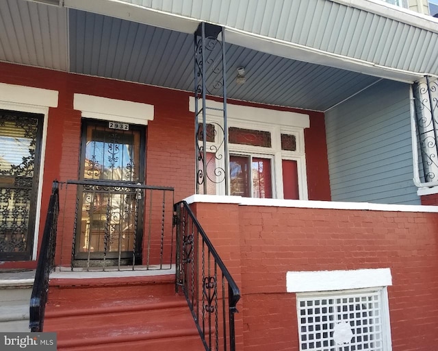 property entrance featuring covered porch and brick siding