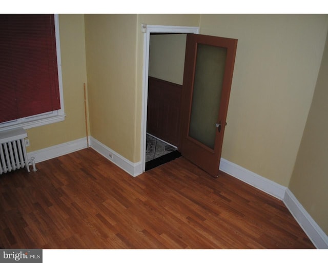 unfurnished room with baseboards, radiator, and wood finished floors