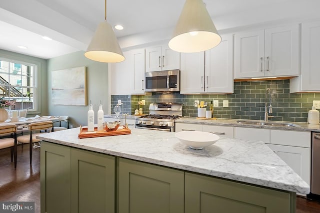 kitchen featuring decorative backsplash, a center island, a sink, white cabinets, and stainless steel appliances