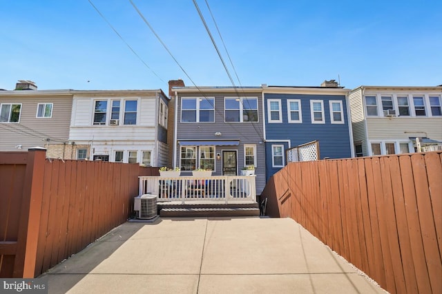 rear view of property with fence, cooling unit, and a patio area