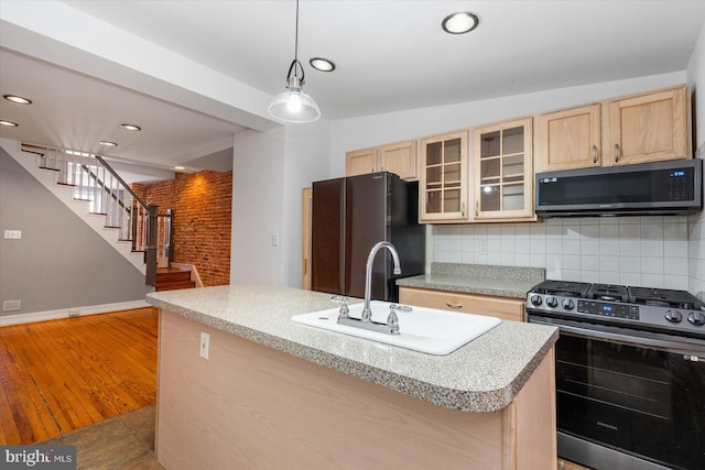 kitchen featuring backsplash, light brown cabinets, stainless steel appliances, and a sink