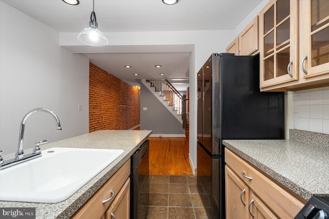 kitchen featuring a sink, backsplash, black dishwasher, glass insert cabinets, and hanging light fixtures