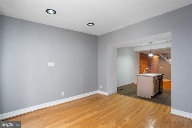 interior space with pendant lighting, hardwood / wood-style floors, baseboards, and a sink