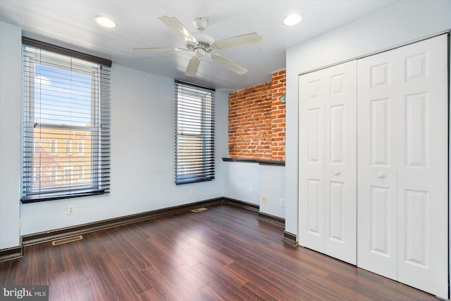 unfurnished bedroom featuring a ceiling fan, baseboards, visible vents, dark wood-type flooring, and a closet