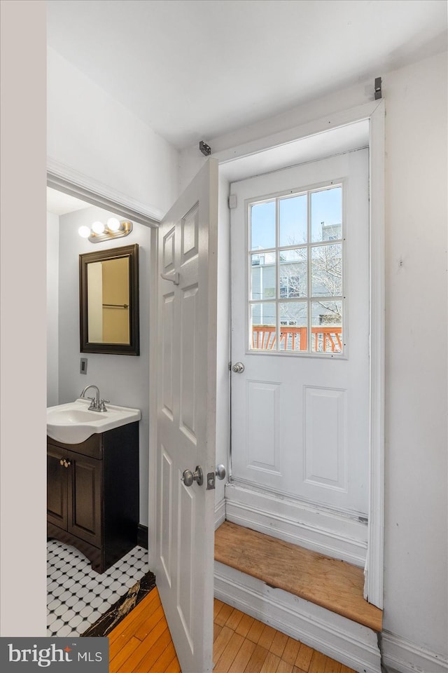 entryway with light wood finished floors, baseboards, and a sink