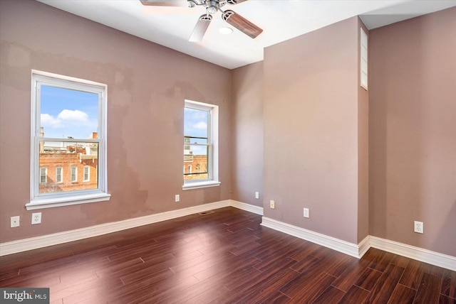 empty room with visible vents, a ceiling fan, baseboards, and dark wood-style flooring