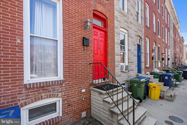 view of exterior entry featuring cooling unit and brick siding