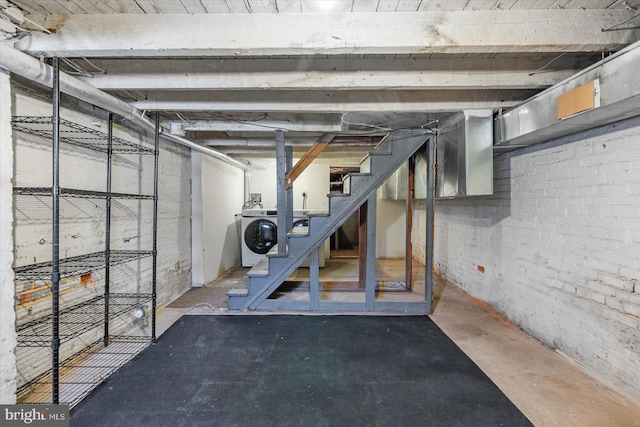 unfinished below grade area featuring stairway and washer / dryer