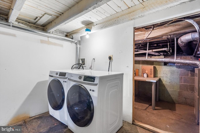 washroom with laundry area, concrete block wall, and independent washer and dryer