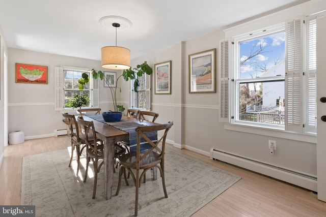 dining room with a baseboard radiator, baseboards, and light wood-style flooring