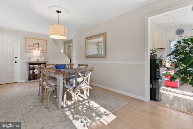 dining space featuring light wood-style flooring and baseboards