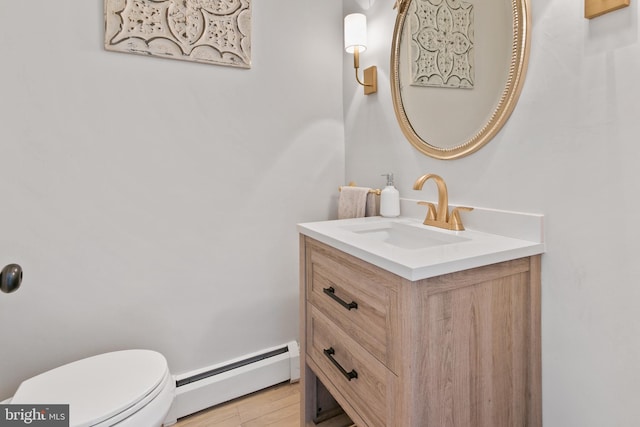 bathroom featuring a baseboard radiator, toilet, wood finished floors, and vanity