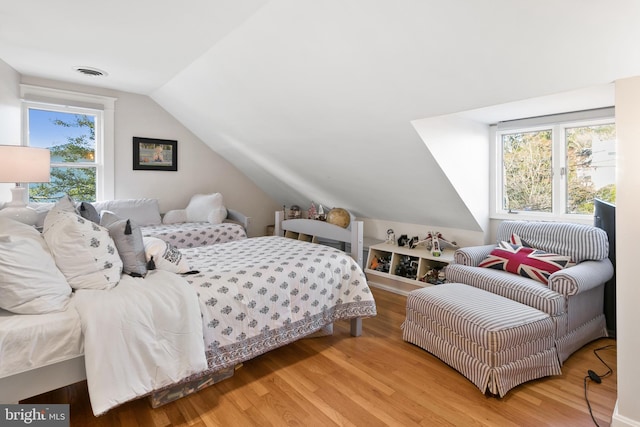 bedroom with lofted ceiling, wood finished floors, and visible vents