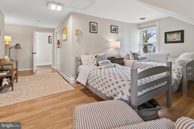 bedroom with visible vents, wood finished floors, baseboards, and a baseboard radiator